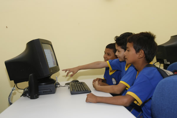 Três alunos da escola Lila Maia School usam um dos computadores conectados à Internet no primeiro laboratório de Informática da escola.