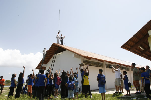 Técnicos instalando a antena receptora na escola Lila Maia